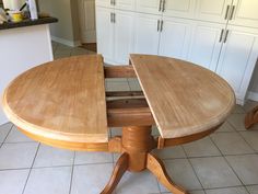 a wooden table with one section missing from the top, in a white kitchen area