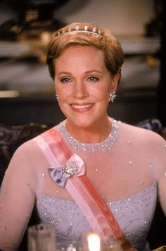 a woman wearing a tiara sitting at a table with a candle in front of her