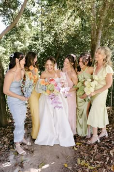 a group of women standing next to each other in front of trees and leaves on the ground