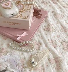 there is a pink box on the bed with pearls and other items around it,