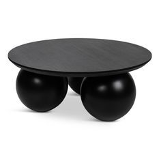 two black balls sitting on top of each other near a table with an oval shape