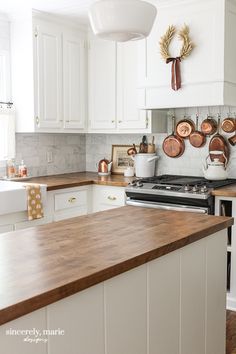 a kitchen with white cabinets and wooden counter tops