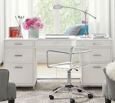 a white desk and chair in front of a window with pink flowers on the windowsill