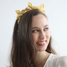 a woman wearing a gold leaf tiara smiling at the camera with her hair blowing in the wind