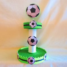 three soccer balls sitting on top of a green cupcake holder that is shaped like a football goal