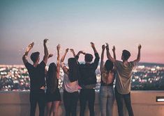 a group of people standing on top of a roof with their hands in the air