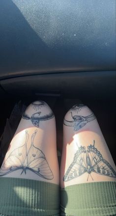 someone with tattoos on their legs is sitting in the back seat of a car and has her feet up