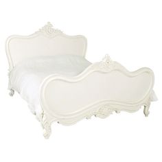 a white bed with an ornate headboard and foot board