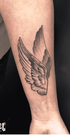 a black and white photo of a wing tattoo on the left leg, with an arrow in the center