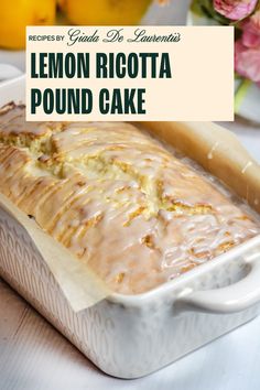 a loaf of lemon ricotta pound cake on a white plate with pink flowers in the background