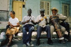 three men sitting on a bench with instruments in their hands and one man holding a drum