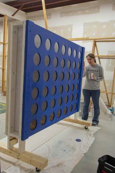 a woman standing next to a giant blue object in a room with construction materials on the floor