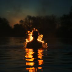 a man is swimming in the water with flames coming out of his head and body