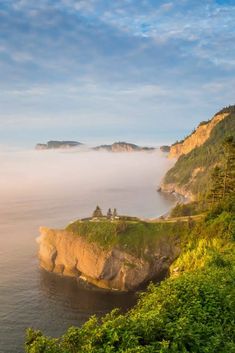 the coast line is covered in fog and low lying clouds as it sits on top of a cliff