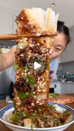 a woman standing over a plate with food on it and chopsticks sticking out of the top