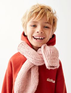 a young boy wearing a red sweater and pink scarf