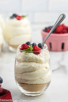 a dessert in a glass with berries and whipped cream on top, next to other desserts