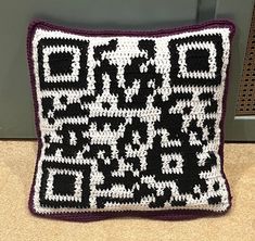 a black and white crocheted pillow sitting on the floor