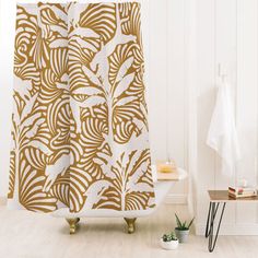 a white and gold shower curtain in a bathroom next to a plant on the floor