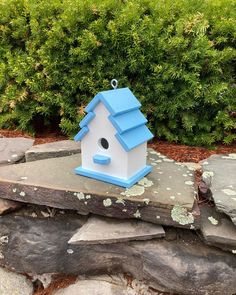 a blue and white birdhouse sitting on top of a stone wall