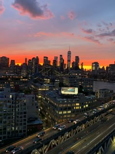 an aerial view of a city at sunset with traffic on the road and skyscrapers in the background