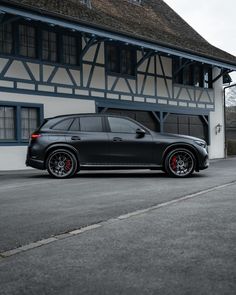 a black car parked in front of a white and blue building with red rims