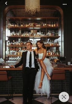 a man and woman standing next to each other in front of a bar