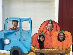 three people are sitting in a fake truck with pumpkins on it