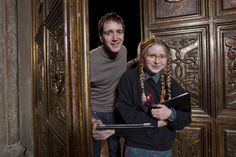 two people standing in front of a wooden door holding a clipboard and smiling at the camera