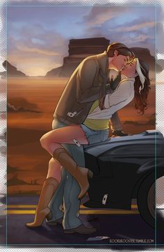 a man kissing a woman on the back of a car in front of a desert landscape