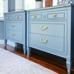 two blue dressers with gold handles in a living room next to a white rug