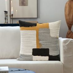 a white couch sitting next to a wooden table with a vase on top of it