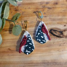 two pieces of fabric hanging from hooks on a wooden table next to a potted plant