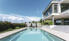 an empty swimming pool in front of a large white house with stairs leading up to it