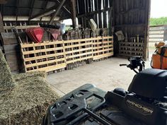 the inside of a barn with hay bales and mowers on it's side