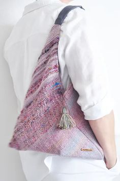 a person wearing a white shirt and tie holding a pink knitted bag with tassels