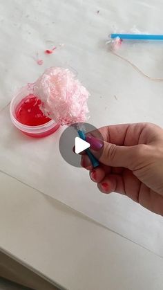 a person holding a toothbrush in front of a bowl of red liquid on a table