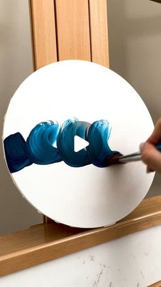 someone is painting something white and blue on the side of a round object with paintbrushes