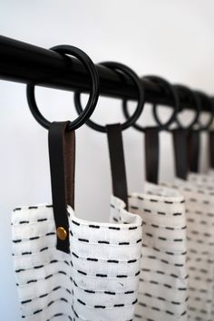 three black and white bags hanging from a metal rack with hooks on the top one