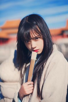 a woman with long black hair holding a book