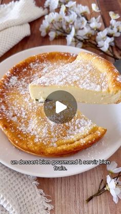 a white plate topped with a piece of pie covered in powdered sugar next to flowers