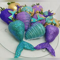 there is a cake decorated with purple, blue and green mermaid tail decorations on the plate