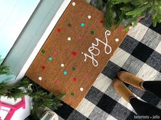 a door mat with the word yes on it next to shoes and christmas tree branches