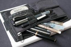 an assortment of pens and pencils in a pouch