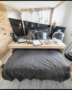 a bed sitting under a wooden shelf next to a lamp on top of a table