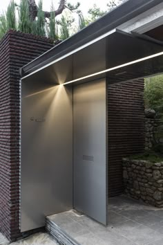 an open metal door on the side of a building with brick walls and stone steps