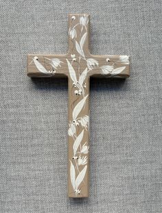 a wooden cross with white flowers painted on it's sides and an arrow in the center