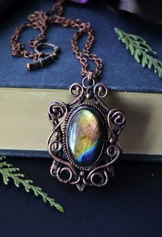 a close up of a book with a chain on it and a rainbow stone in the center