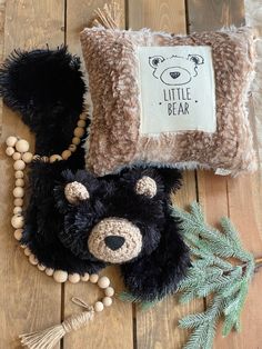 a stuffed bear is laying on the floor next to a pillow and bead necklace