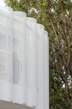 a man standing on top of a window sill next to a tall white building